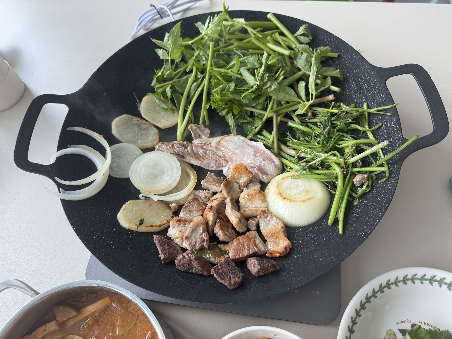 Samgyeopsal, beef sirloin and minari on the grill pan